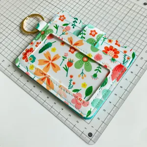 Floral print card holder detail view with clear ID window, card slots and gold keyring.