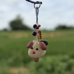 Dettaglio del ciondolo portachiavi a forma di animale in semi naturali e guscio di noce di cocco.
