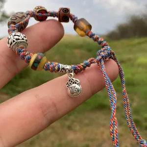 Pulsera de la suerte trenzada tibetana hecha a mano con cuentas de colores y colgante.