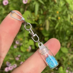 Detailaufnahme eines Mini-Glas-Wunschflaschen-Schlüsselanhängers mit blauen Sternen.