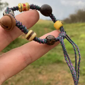 Pulsera trenzada tibetana hecha a mano con cordones de colores y cuentas étnicas vintage.