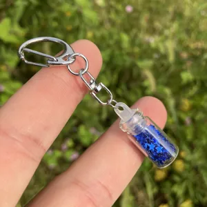 Nahaufnahme eines klaren Glas-Wunschflaschen-Schlüsselanhängers mit blauen Sternen.