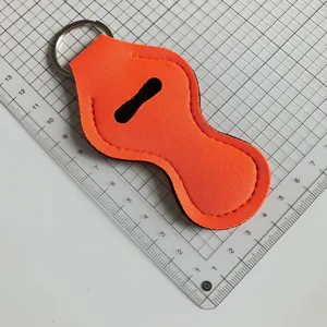 Détail de porte-baume à lèvres en néoprène orange vif avec coutures propres et anneau porte-clés.