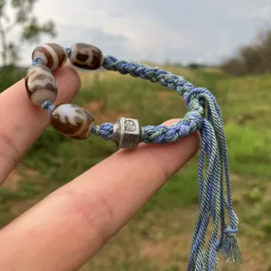 Pulsera tibetana trenzada a mano de estilo étnico con cuentas y borlas en la muñeca.