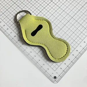 Détail de l'étui à rouge à lèvres en néoprène jaune-vert avec anneau porte-clés métallique.
