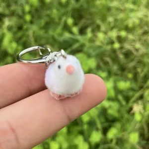 Cute fluffy bird keychain detail view, soft miniature animal pendant hanging charm close up.