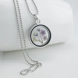 Exquisite dried flower glass locket necklace with silver bead chain, elegant floral jewelry.