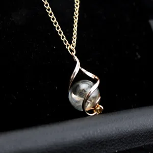 Gold chain necklace featuring a spiral pendant with a clear glass ball and dandelion seed.