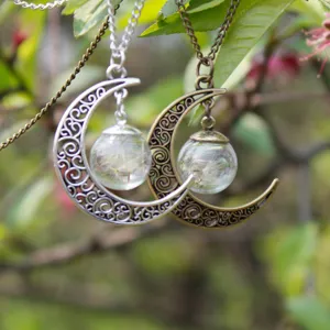 Dettaglio ravvicinato della collana con sfera di vetro a mezzaluna e semi di tarassaco dentro.