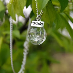 Close-up detail of forest style dandelion seed glass ball necklace with wish metal tag decoration.