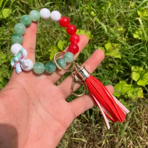 Detail shot of colorful beaded wristlet keychain featuring red PU leather tassel and bow charm.