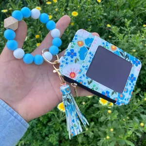 Portacarte con motivo floreale e portachiavi bracciale in perole di silicone con nappa.