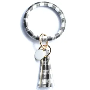 Bracciale portachiavi rotondo in pelle a quadri bianco e nero con nappina e chiusura in metallo.