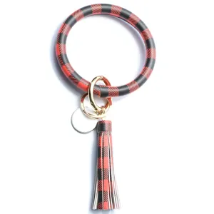 Bracciale portachiavi in pelle a quadri rossi e neri con nappa e dettaglio ciondolo.