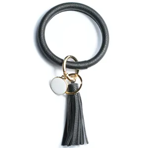 Détail en gros plan du porte-clés bracelet en cuir PU noir avec pompon et anneaux métalliques.