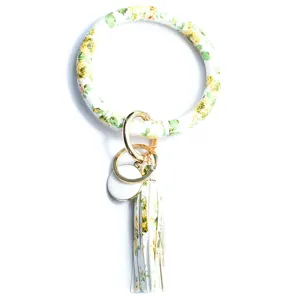 Vue détaillée du porte-clés rond en cuir PU à imprimé floral jaune avec pompon et anneaux.
