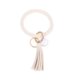 Close-up van beige PU lederen O-ring sleutelhanger met gouden ring en kwastje detail.