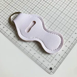 Étui en néoprène pour baume à lèvres avec anneau métallique pour clés sur tapis de découpe