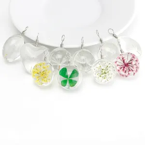 Clear glass dried flower pendant featuring real dandelions and clovers for elegant nature jewelry.