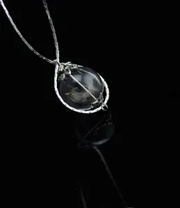 Squisito primo piano dettagliato di una collana con ciondolo globo di vetro di tarassaco.