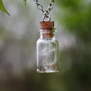 Close-up detail of a clear glass bottle pendant necklace filled with delicate dandelion seeds.