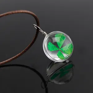 Transparent glass sphere necklace featuring a natural green four leaf clover specimen pendant.