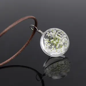 Dried flower glass ball necklace detail, featuring natural plant specimen inside a clear orb.