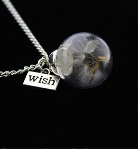 Dandelion glass globe pendant necklace with a wish tag, delicate floral jewelry detail.