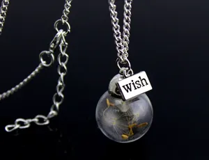 Detailed shot of a silver necklace with a glass ball pendant containing dandelion seeds and wish tag.