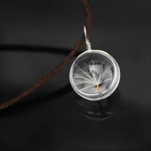 Close-up detail of a clear glass globe pendant featuring a delicate natural dandelion seed inside.