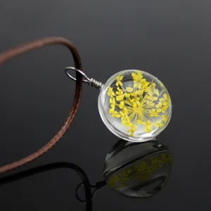 Close-up detail of the transparent glass globe pendant featuring yellow dried flowers.