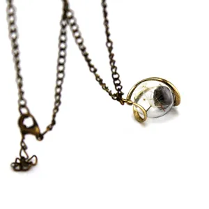 Close-up detail of vintage bronze dandelion seed glass ball pendant necklace plant jewelry.