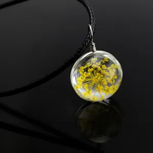 Detailed macro shot of a delicate glass ball pendant necklace filled with pretty yellow dried flowers.