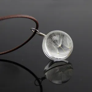 Close-up of a clear glass ball pendant necklace featuring real dandelion seeds inside.