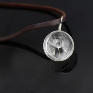 Close-up detail of clear glass ball pendant with natural dandelion seeds and brown leather cord.