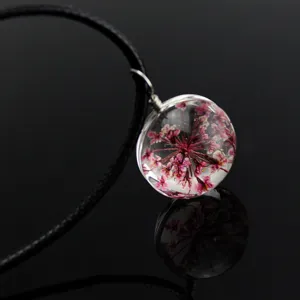 Exquisite transparent glass sphere pendant featuring delicate pink dried flower specimens inside.