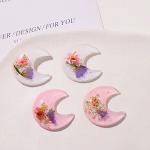 Resin dried flower crescent moon charm detail, pink and white DIY phone case and earring parts.