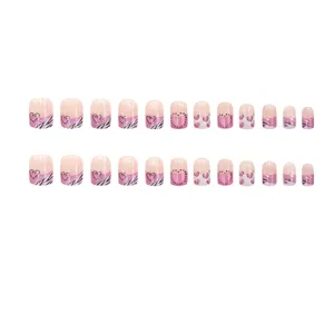 Dettaglio in primo piano del set di unghie finte con motivo zebrato e cuore rosa.