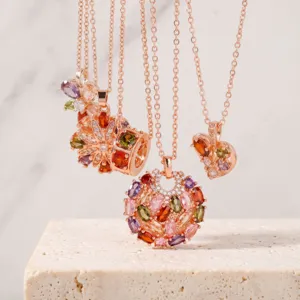 Primo piano dettagliato di collane con ciondolo in oro rosa e zirconi multicolore con motivi floreali.