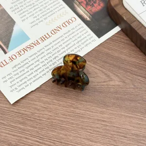 Detailed shot of a small tortoiseshell acetate hair claw clip, minimalist design for daily wear.