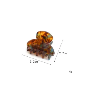 Detail view of the small acetate hair claw showing tortoise shell texture and compact size.