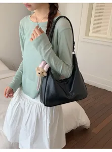Detailed view of a fashionable black shoulder bag with cute bear pendant for daily commuting.