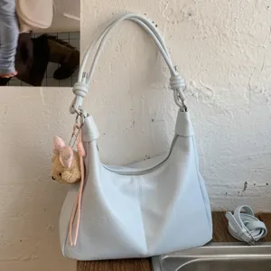 Light blue slouchy shoulder bag for women, casual hobo tote with cute plush charm and knot strap.