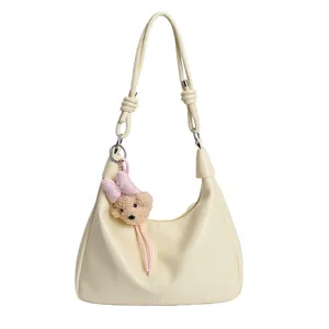 Minimalist cream hobo shoulder bag with cute bear keychain for stylish women daily use.