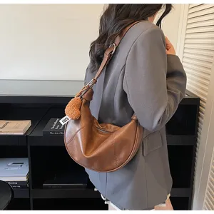 Brown hobo shoulder bag detail, stylish crescent shape with cute heart charm for daily wear.