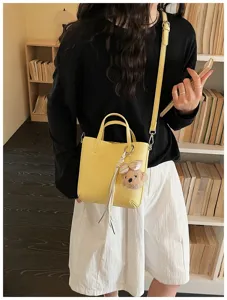 Yellow PU leather handbag detail showing shoulder strap and cute bear plush pendant accessory.