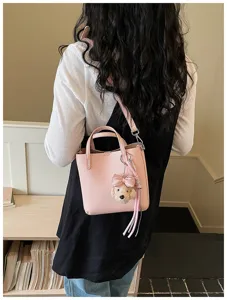 Pink leather bucket bag detail view with cute plush dog pendant and comfortable shoulder strap.