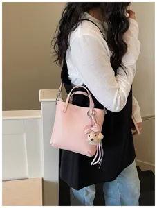 Detail shot of pink leather bucket bag with cute bear charm, casual style for daily commuting.
