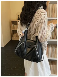 Stylish black PU leather shoulder bag with chic front zip pockets and cute plush pendant charm.