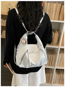 Detail view of white convertible women backpack, casual hobo shoulder bag with plush charm.